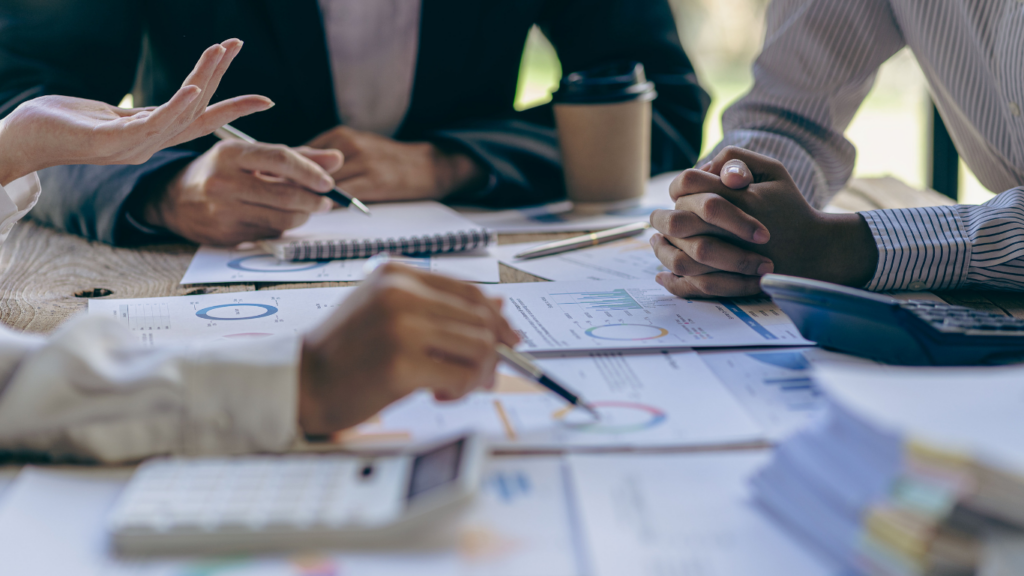 business people look at paperwork at a table, discussing options