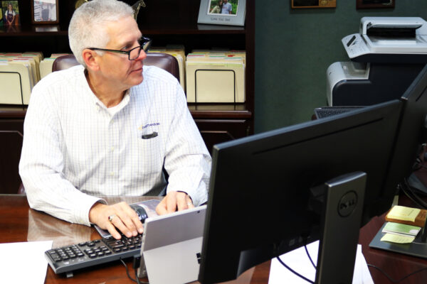 A man with glasses types on computer looking at the screen